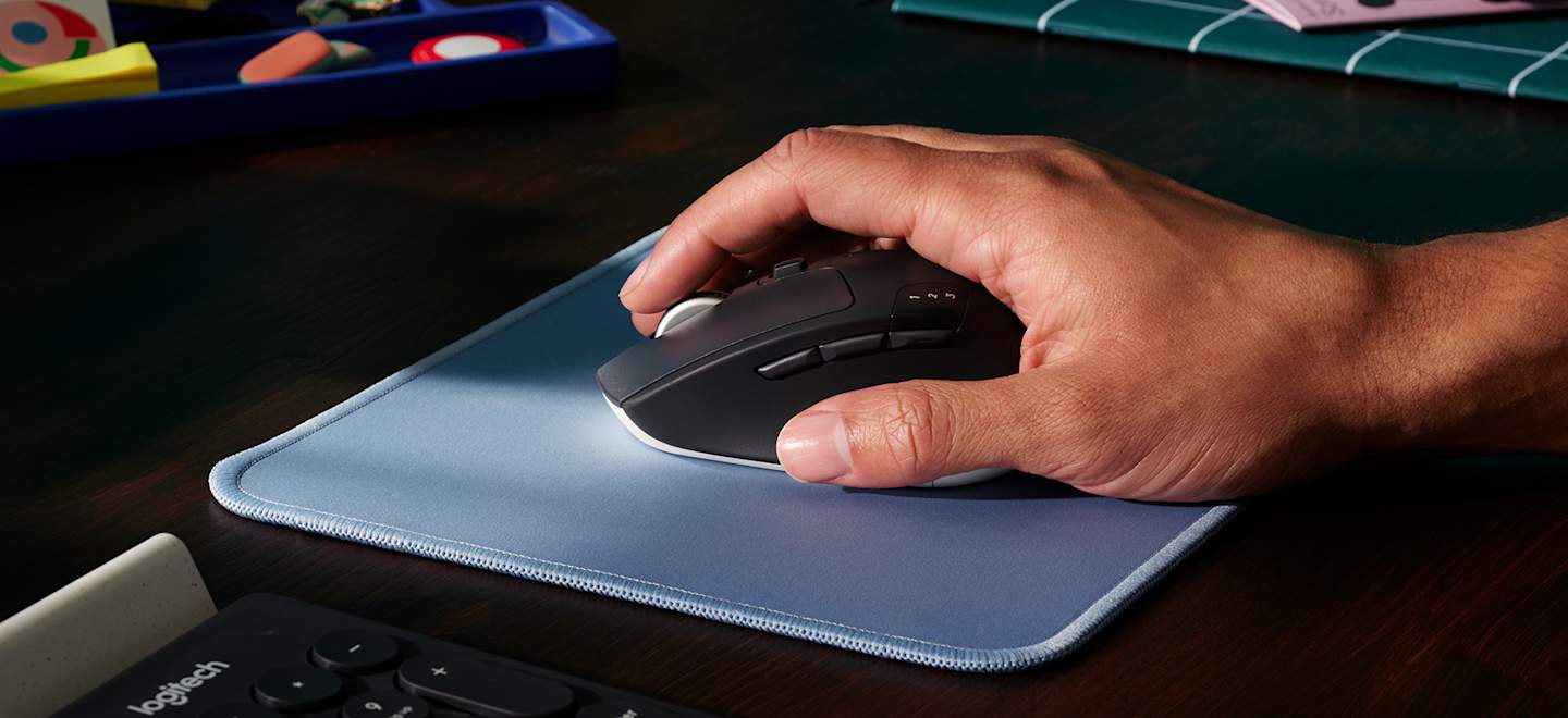 Logitech M720 Triathlon mouse in use at a desk, in an official manufacturer photograph